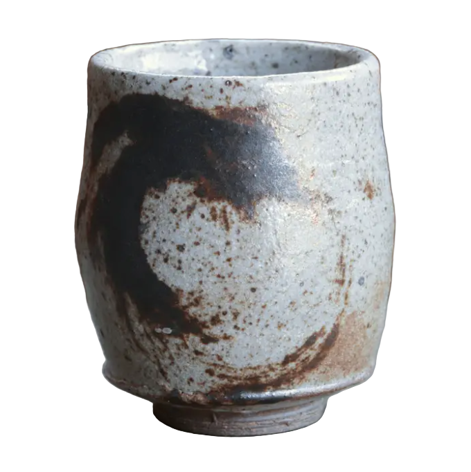 Ceramic cup with speckled glaze on a textured surface
