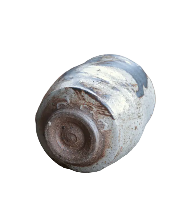 Cylindrical ceramic object with a rustic finish on a textured surface